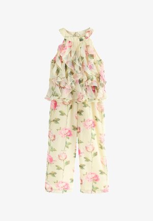 Mouwloze crèmekleurige jumpsuit met roze rozenprint en gerimpelde, gelaagde chiffon top, met groene bladeren en verspreide tekst.