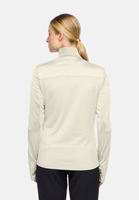 Lichtbeige longsleeve top met hoge kraag, gladde textuur en aansluitend ontwerp; heeft een naadloze achterkant en zachte stof voor comfort.