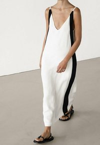 Hvid ærmeløs kjole med dyb V-udskæring, med sorte sidestreger, lavet af glat stof, ankellængde med en afslappet pasform.