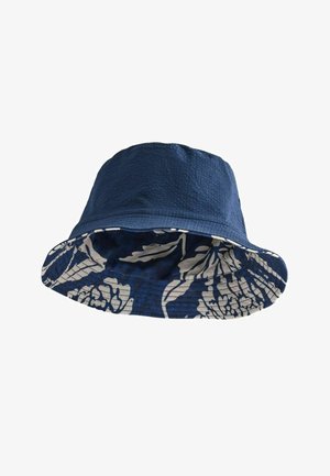 Reversible navy bucket hat with textured fabric on top and white floral pattern on the brim's underside.