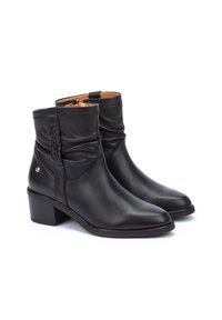 Botas de cuero negras hasta el tobillo con un diseño arrugado y un detalle trenzado en el costado. Cuentan con un tacón cuadrado y una cremallera lateral para el cierre.