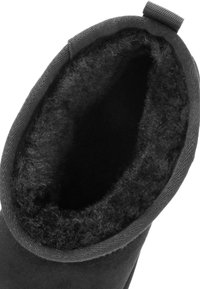 Binnenkant van zwarte suede laarzen met een zachte, fuzzy voering en een stevige afbinding. De bovenkant heeft een textiele trekband voor eenvoudig aan- en uittrekken.
