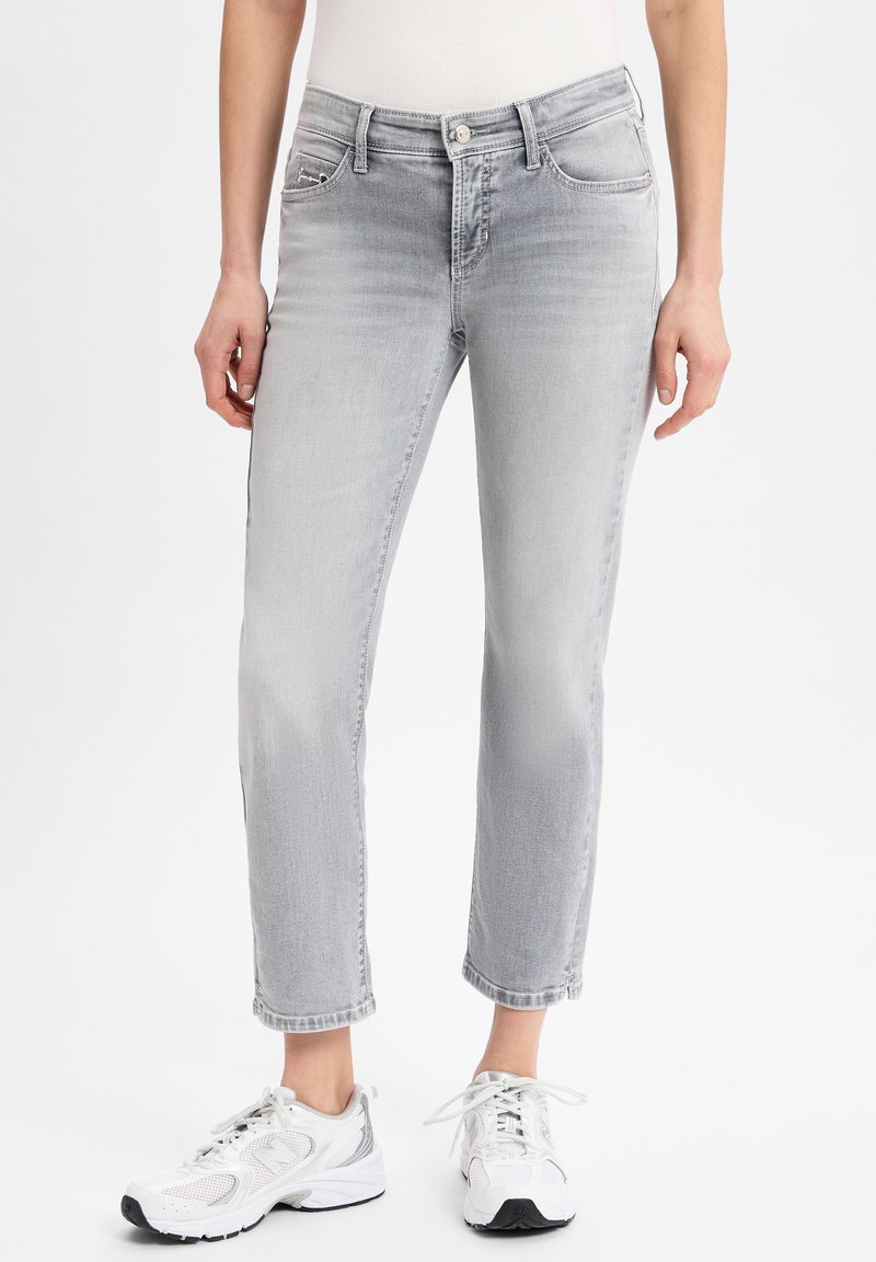 Light grey jeans made of denim, featuring a slim fit, faded areas, five pockets, and rolled hems, paired with white sneakers.