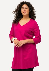 Fuchsia V-hals tuniek met driekwartmouwen, van zacht katoen, losse pasvorm en een zoom die onder de heupen uitkomt.