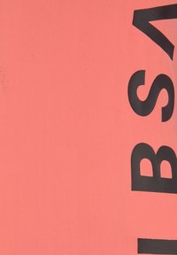 Koraalroze stoffen t-shirt met gedurfde zwarte blokletters. Het materiaal is soepel, rekbaar en heeft een lichte textuur.