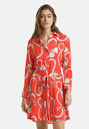 Robe-shirt rouge avec un motif de corde, manches longues, fermeture à boutons et ceinture à la taille. Fabriquée en tissu lisse et léger.