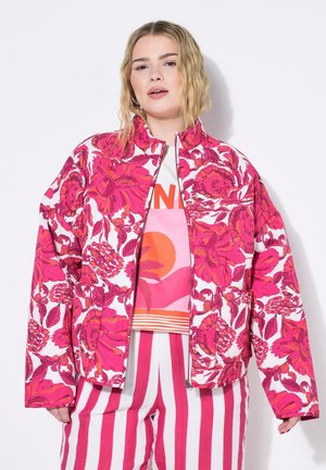 Veste à imprimé floral en tissu rose et blanc, avec un col haut, une fermeture éclair et deux poches latérales. Les motifs comprennent de grandes fleurs.