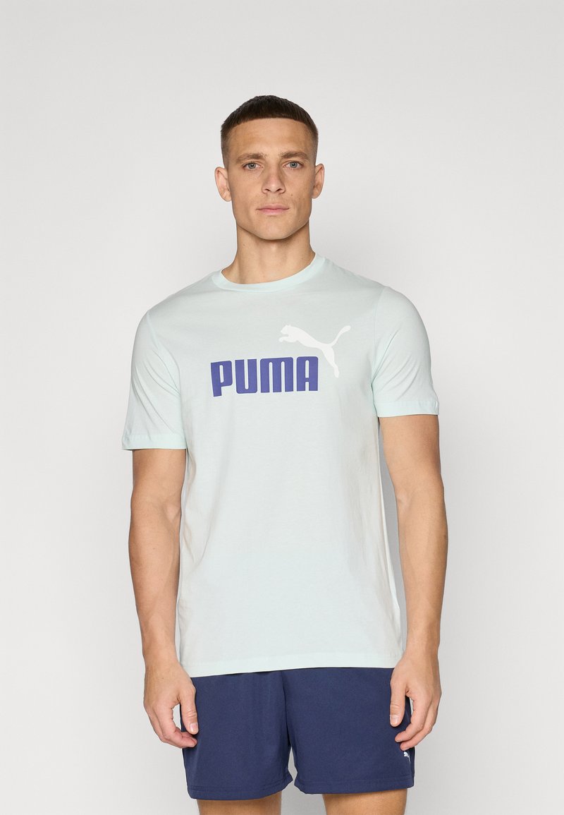 Šviesiai mėlyna medvilninė marškinėliai su dideliu tamsiai mėlynu "PUMA" logotipu ir baltu puikiai puma siluetu kairėje pusėje. Trumpomis rankovėmis ir apvaliu iškirpimu.