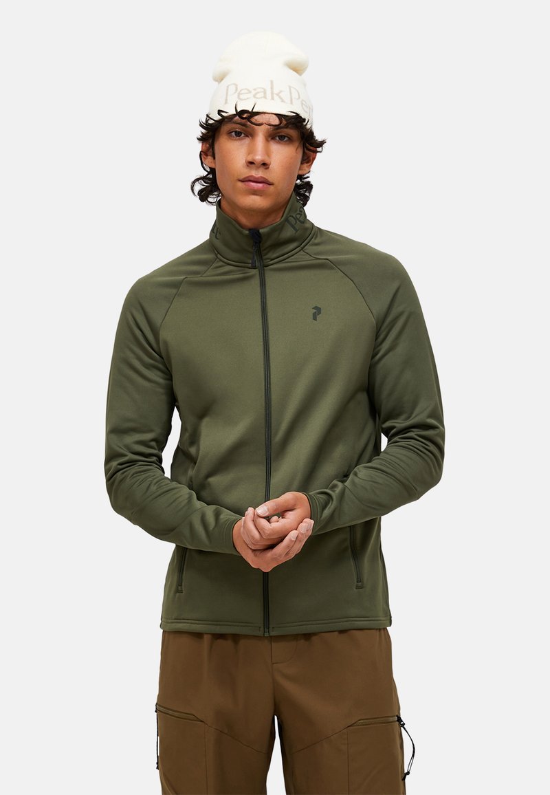 Giacca verde oliva con zip e colletto alto, realizzata in tessuto liscio; presenta tasche laterali, un piccolo logo sul lato sinistro del petto e aperture per i pollici.