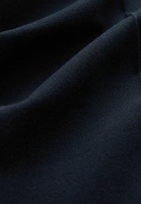 Must mustr fabric, mille pehme tekstuuriga, näidates õrnu volte ja peent läiget. Pole nähtavaid mustreid ega riistvara detaile.