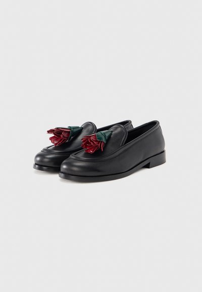 Mocassins de pele preta com bico arredondado, salto plano e detalhes decorativos de flores borgonha com folhas verdes na parte superior.
