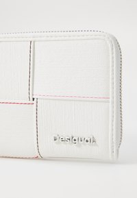 White zip-around wallet with textured fabric, featuring a stitched pattern and a raised silver "Desigual" logo on the front.