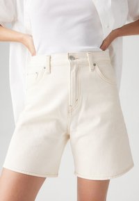 Σορτς από τζιν σε κρεμ απόχρωση με ψηλή μέση, διαθέτουν κούμπωμα με κουμπί μπροστά, πέντε τσέπες και αντίθετη ραφή. Λείο ύφασμα.