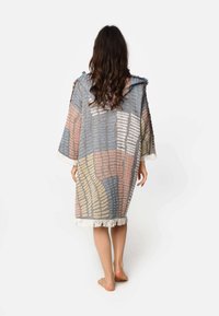 Višebojni kaput s kapuljačom, s geometrijskim uzorkom od mekanog materijala, s resicama na rubovima u krem boji i opuštenim, lepršavim siluetom.