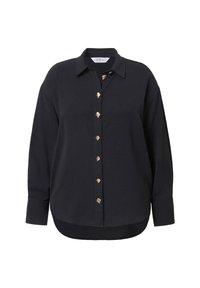 Camisa de gran tamaño de color oscuro, con cuello y botones decorativos dorados en la parte frontal, tela texturada y un dobladillo curvado.