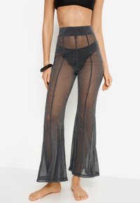 Παντελόνια καμπάνα με ψηλή μέση, φτιαγμένα από διαφανές μαύρο ύφασμα με ασημένιες λάμψεις, με κάθετα μοτίβα και φαρδιά γραμμή ποδιού.