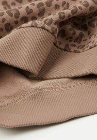 Hnědá mikina s leopardím vzorem, s žebrovanými manžetami a lemem, měkkou texturou a hladkým podšívkou.