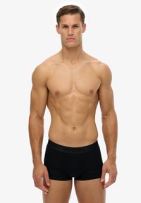 Boxer-briefs noirs avec ceinture élastique arborant un logo en relief. Tissu en coton doux, coupe ajustée et longueur mi-cuisse.