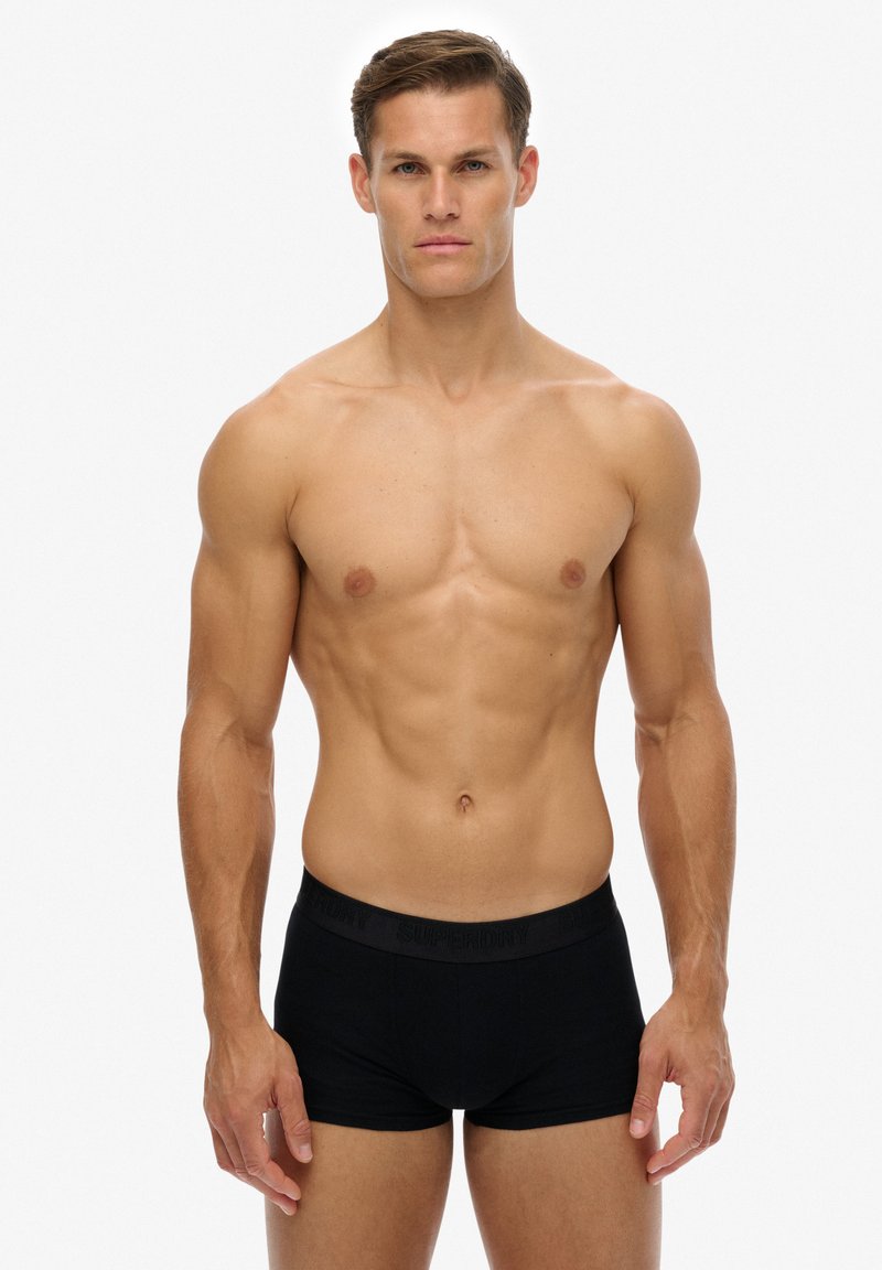 Boxer-briefs noirs avec ceinture élastique arborant un logo en relief. Tissu en coton doux, coupe ajustée et longueur mi-cuisse.