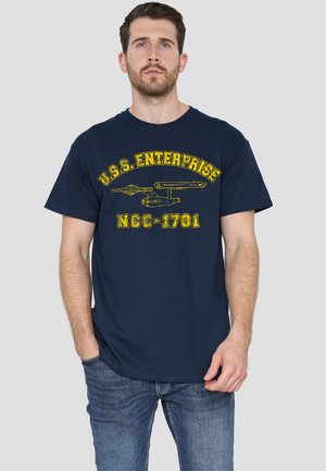 Navy cotton t-shirt featuring a yellow graphic of the U.S.S. Enterprise and text "U.S.S. ENTERPRISE NGC-1701" in a distressed font.
