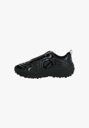 Schwarzer Slip-On Sneaker mit glänzender Oberfläche, strukturierten Wellenmustern und einer klobigen Gummisohle mit runden Rillen. Minimalistisches Design.