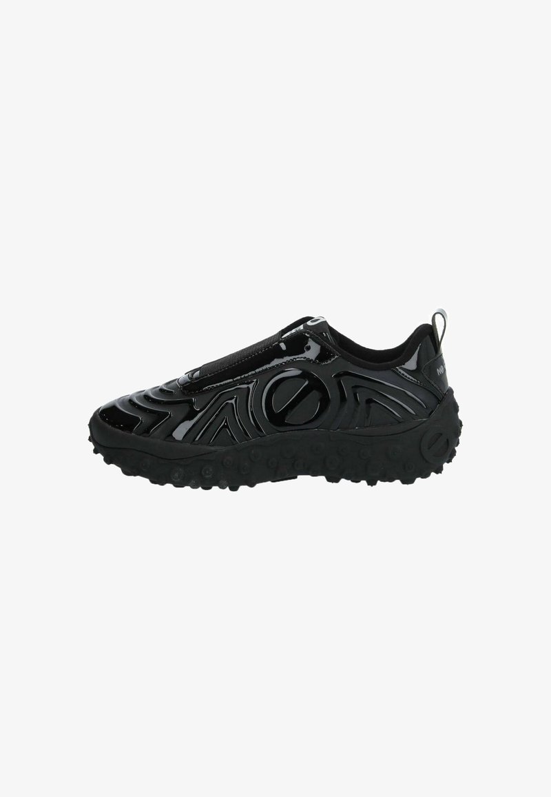 Black slip-on sneaker with glossy surface, textured wave patterns, and a chunky rubber sole featuring circular grips. Minimalist design.
