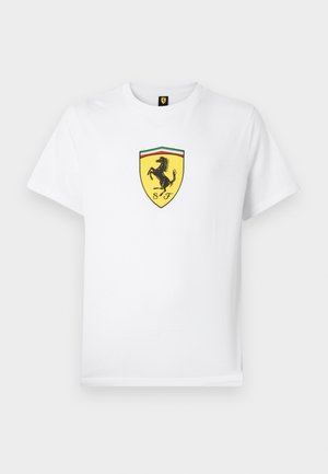 Valkoinen puuvillainen t-paita, jossa on musta-keltainen Ferrarin logo, jossa on takajaloilleen nouseva hevonen kilven muotoisessa kentässä ja yläosassa vihreä-puna-vihreä raita.