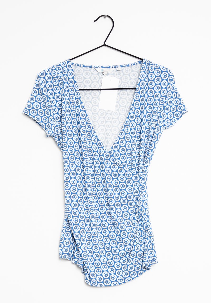 Body en tissu bleu à motifs avec un col en V, des manches courtes et des motifs circulaires dans différentes nuances de bleu et de blanc. Étiquette attachée.