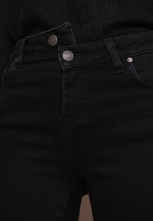 Czarne dżinsy mają wysoką talię z zapięciem na guziki, wyraźne szwy oraz gładką, lekko teksturowaną powierzchnię.