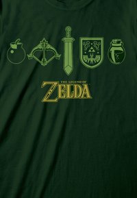 Zelené bavlněné tričko s čtyřmi ikonickými prvky: bombou, lukem, mečem a štítem, s textem "The Legend of Zelda" ve zlatém písmu.