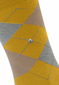 Skarpetki w wielokolorowy argyle z żółtymi, szarymi i beżowymi rombami, z niebieskimi przeszyciami i małym metalowym akcentem logo.