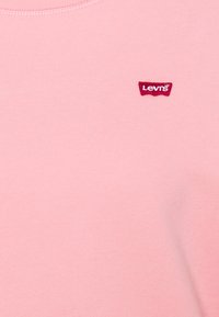 T-shirt in cotone rosa con collo tondo, maniche corte e una piccola etichetta rossa con il logo Levi's cucita sulla parte sinistra del petto.