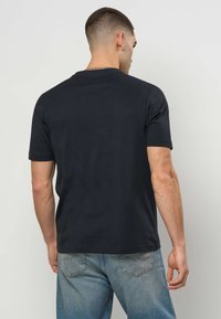 Čierne bavlnené tričko s krátkymi rukávmi, okrúhlym výstrihom a klasickým strihom. Zadná časť má hladký povrch bez viditeľného loga.