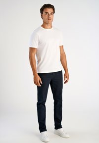 Valkoinen puuvillapaita, pyöreä kaula-aukko, lyhyet hihat, yhdistetty tummansinisiin farkkuihin ja valkoisiin tennareihin. Siistit linjat, rento istuvuus.