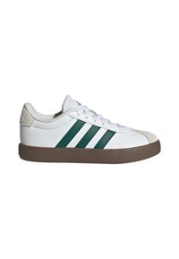 Baskets basses blanches avec bandes Adidas vertes, semelle marron, lacets blancs et détails en daim sur les doigts de pied et le talon.
