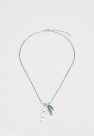 Collana in argento con ciondolo del logo Lacoste e un charm a forma di coccodrillo verde, che mostra un design elegante e elementi testurizzati.