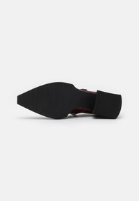 Red leather high-heeled shoe with a black rubber sole. Includes a textured outsole for grip and a chunky heel design.