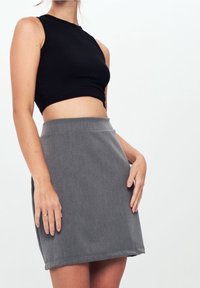 Crop top nero a coste abbinato a una gonna grigia a vita alta. La gonna ha una texture liscia e un design pulito e minimalista.