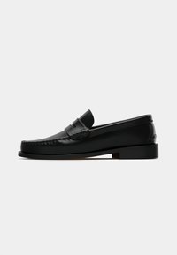 Melni ādas loafers ar gludu apdari, kas iekļauj stitched šuvīti gar purngalu un zemu, bloku papēdi. Klasisks dizains un minimālists stils.