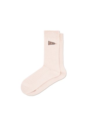 Light pink ribbed cotton crew socks with a small brown logo tag reading "LES DEUX" near the calf. Soft texture, standard sock shape.