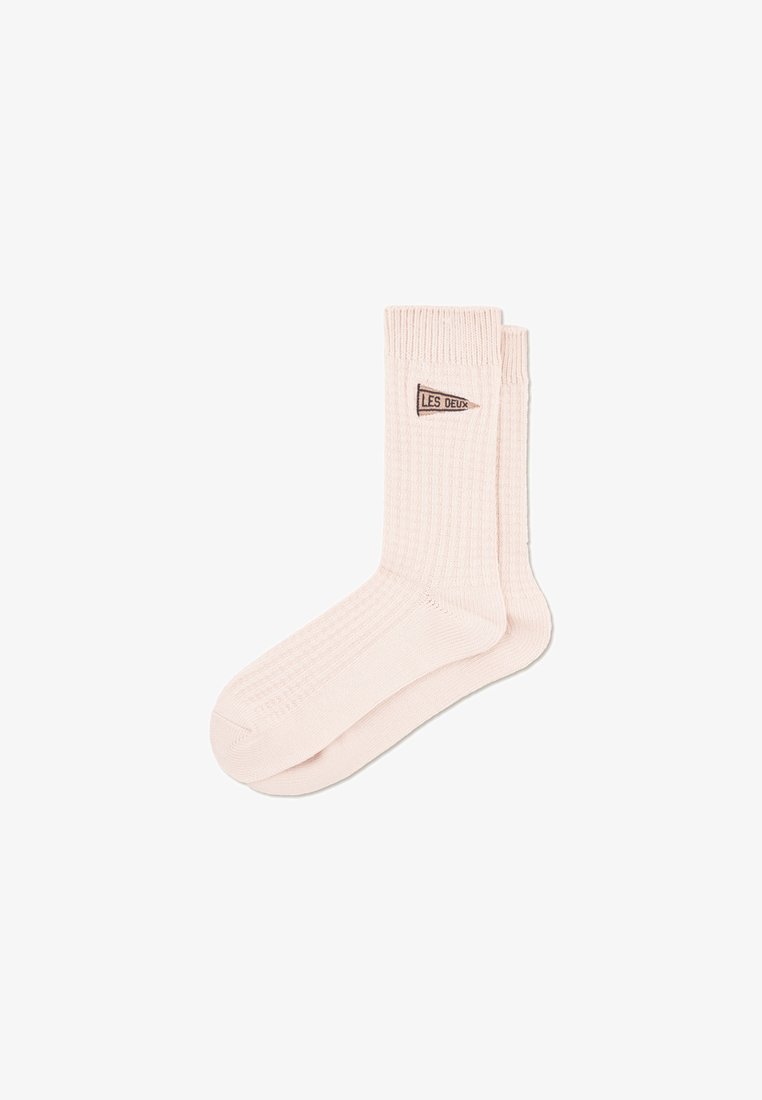 Socks crew de algodão ribado em rosa claro com uma pequena etiqueta de logo castanha a dizer "LES DEUX" perto da panturrilha. Textura macia, forma de meia standard.