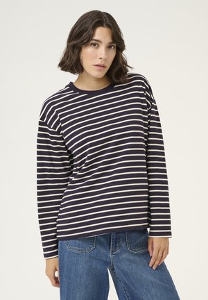 Navy striped long-sleeve top with white horizontal stripes, round neckline, relaxed fit, and soft fabric texture. Paired with blue jeans.