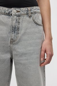 Jeans de mezclilla gris claro con cintura alta, con cierre de botón, diseño de cinco bolsillos y detalles de costura visibles. Textura suave.