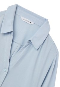 Camicia azzurro chiaro a maniche lunghe con colletto, chiusura a bottoni e una texture di tessuto morbido. Etichetta con la scritta "Terranova," taglia S.