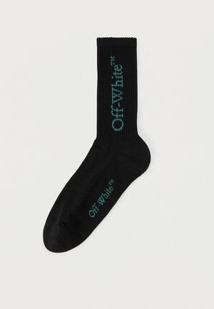 Chaussette noire à tige côtelée, avec le logo « Off-White » en bleu sarcelle sur la jambe et le pied.