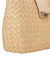 Sac à main en paille tissée beige avec un motif en chevrons, disposant d'une poignée en cuir lisse et d'un accent en métal avec le logo sur le côté.