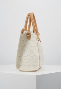 Beige tote-väska med mönstrad tyg och bruna läderhandtag. Har en strukturerad form och en subtil logodesign. Metallaccent på toppen.