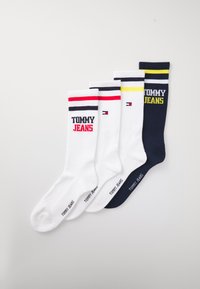 Fire par sokker i hvid, marineblå og farveblokkerede designs, med ribbet tekstur og broderet "TOMMY JEANS" logo.