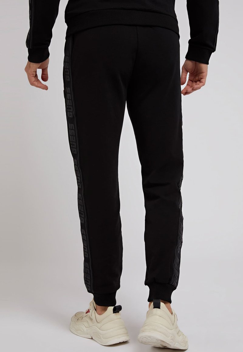 Herren Trainingsanzüge | Guess LOGO BAND Jogginghose schwarz - US00492 Herren Trainingsanzüge | Guess LOGO BAND Jogginghose schwarz - US00492