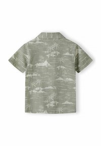 Camicetta a maniche corte di colore verde chiaro con stampa di un paesaggio tropicale bianco, che include isole e palme. Collo classico e orlo dritto.